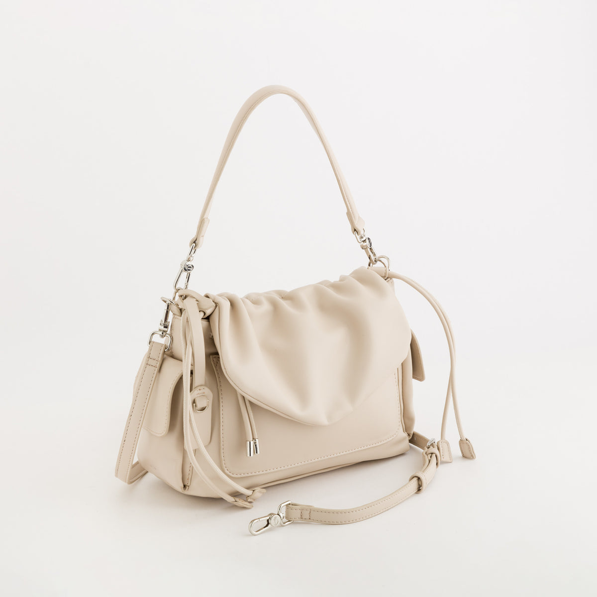A light beige leather shoulder bag with a slouchy, draped front flap, a top handle, and an adjustable shoulder strap with silver-tone hardware, shown on a clean white background.