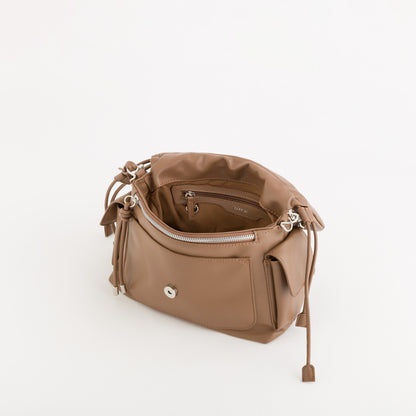 A tan leather bucket bag shown from an overhead angle, open to reveal its interior zippered pocket and drawstring details, set against a plain white background.