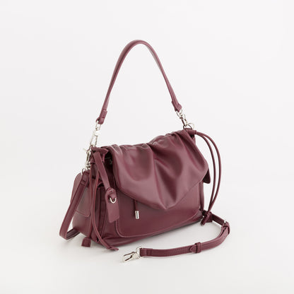 A burgundy leather shoulder bag with a slouchy, draped design, featuring a top handle, a detachable shoulder strap, and silver-tone hardware, photographed on a clean white background.